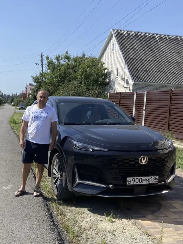 Покупатель рядом с полученным автомобилем Changan